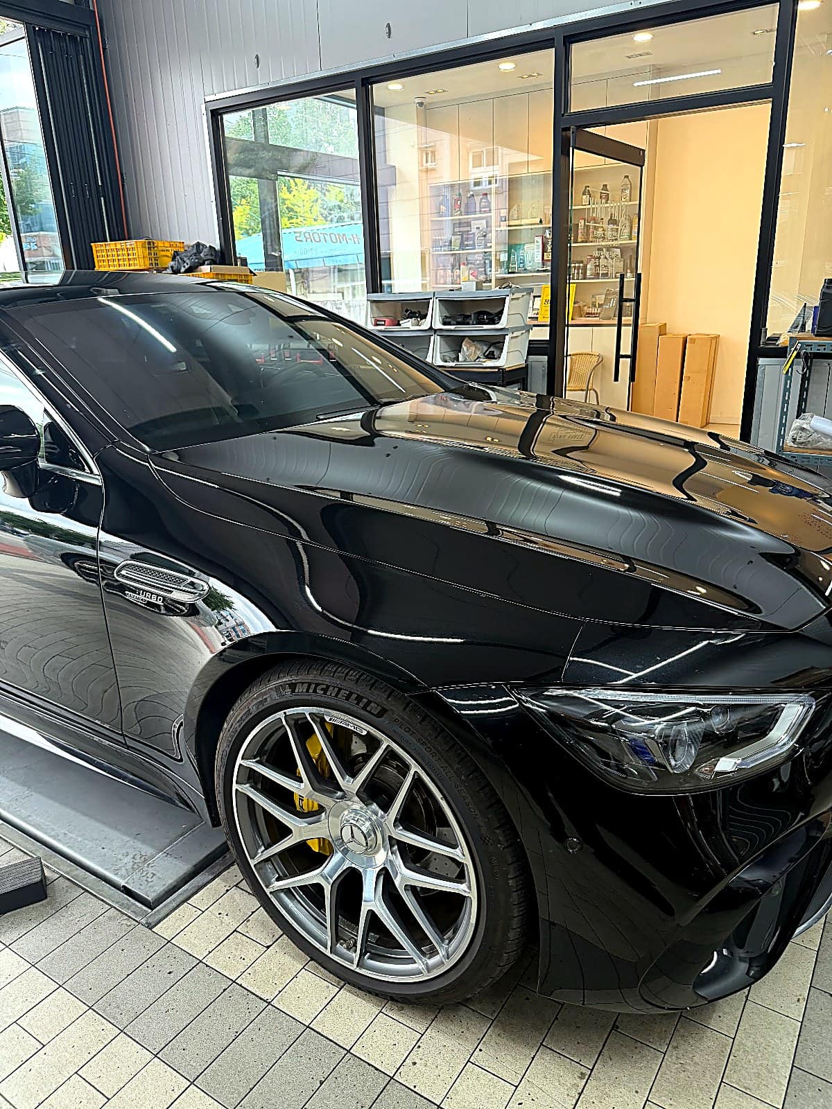 입고된 검정색 메르세데스-AMG GT 43 4도어 쿠페 측면, 노란 캘리퍼가 보이는 모습