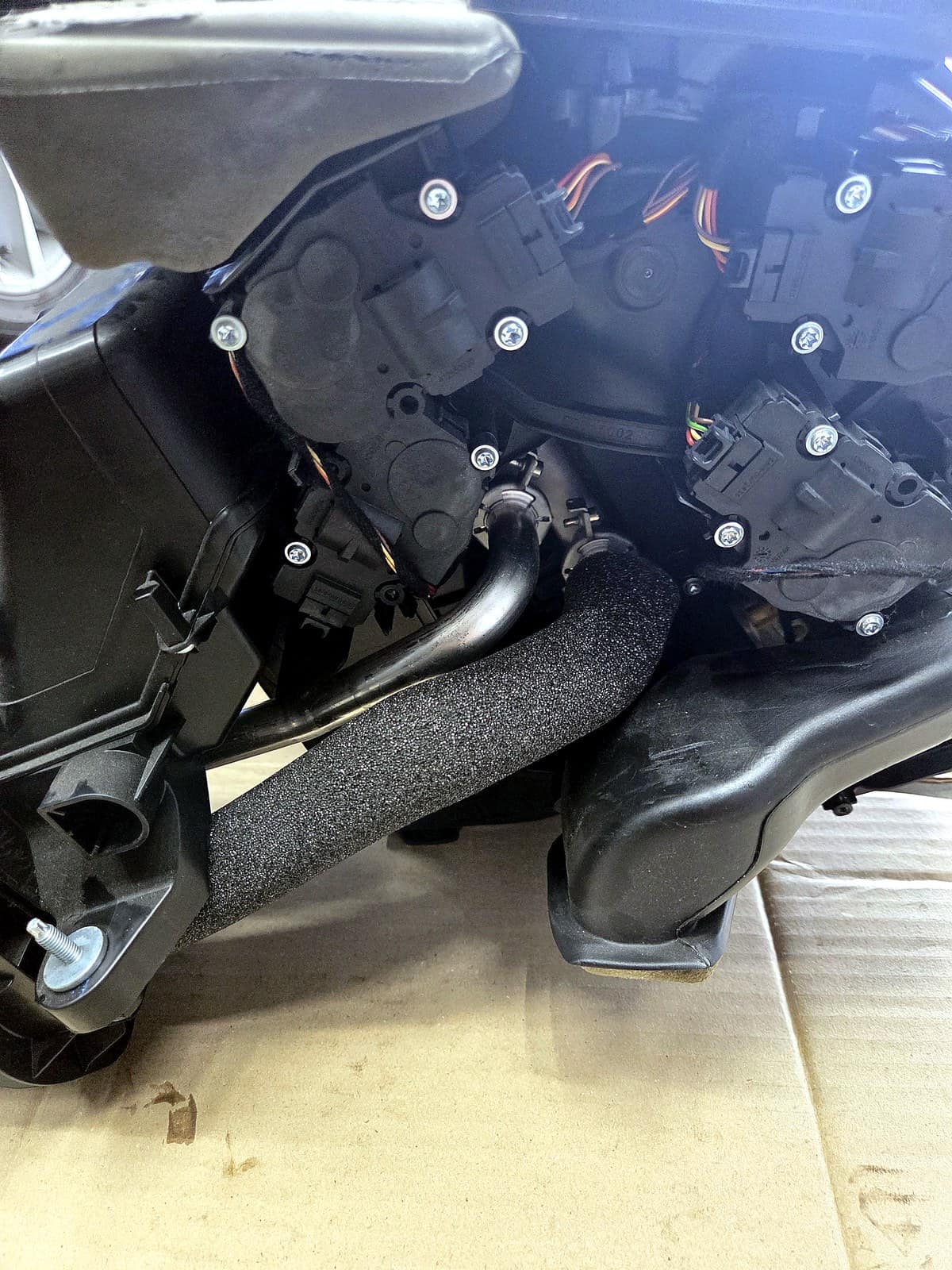 대시보드에서 분리해 작업대에 올려놓은 HVAC 하우징, 여러 개의 액추에이터 모터가 보이는 모습