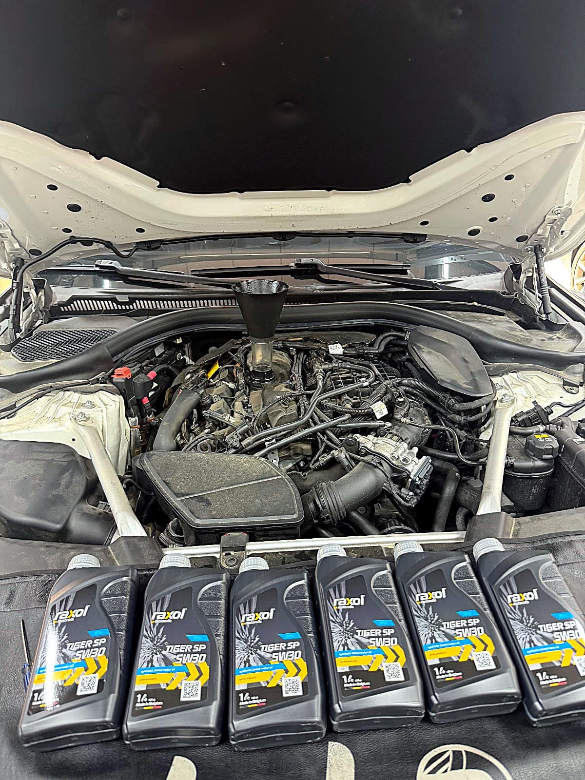 BMW 520i에 넣을 새 엔진오일 용기들과 엔진룸