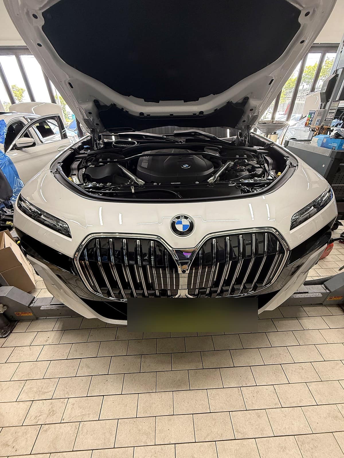 리프트에 올라간 BMW 740i xDrive 보닛을 열고 엔진오일 교환을 준비하는 모습