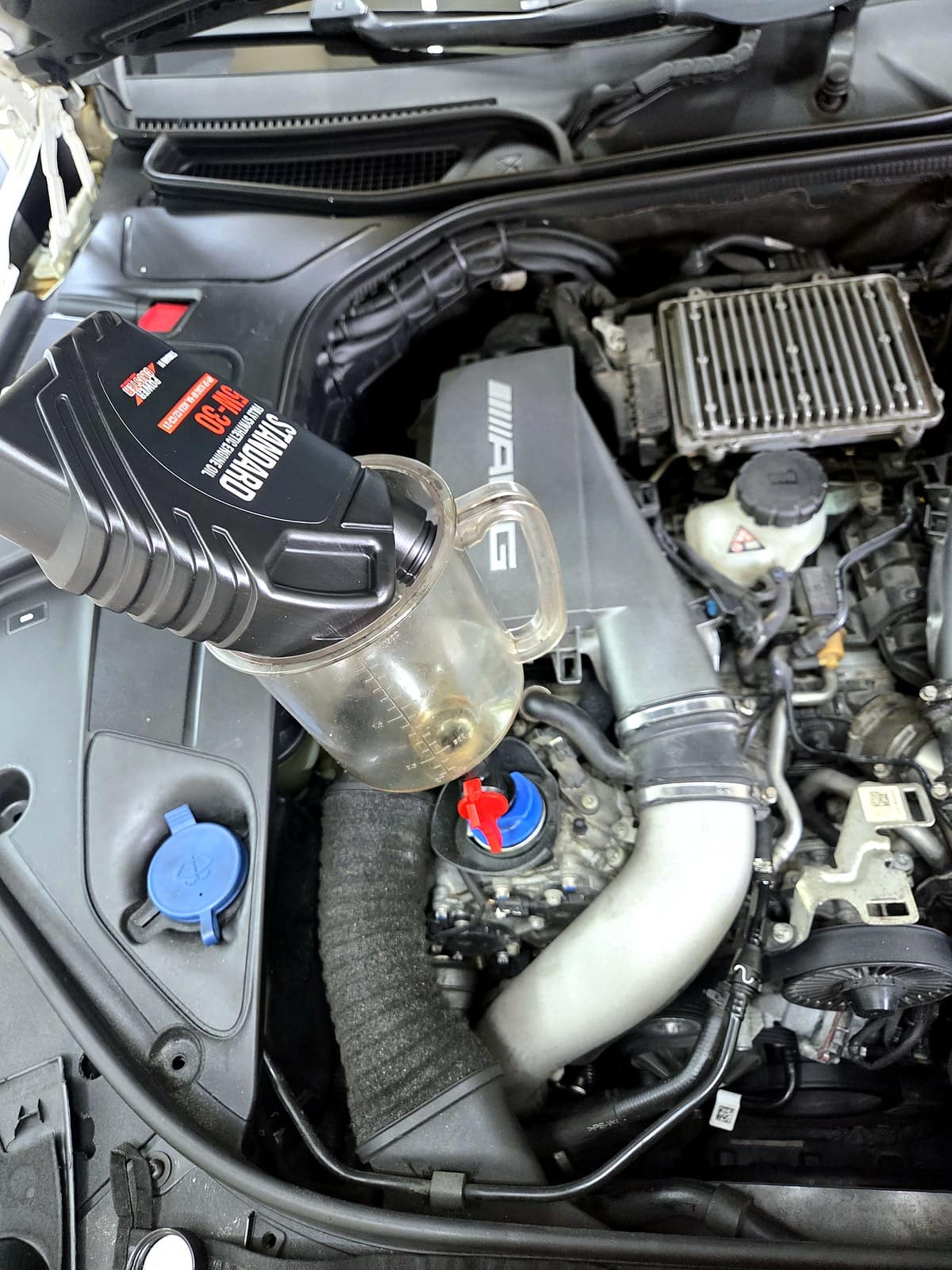 벤츠 S63 AMG 엔진룸에 5W-30 합성유를 주입하는 모습, AMG 엔진커버가 보인다
