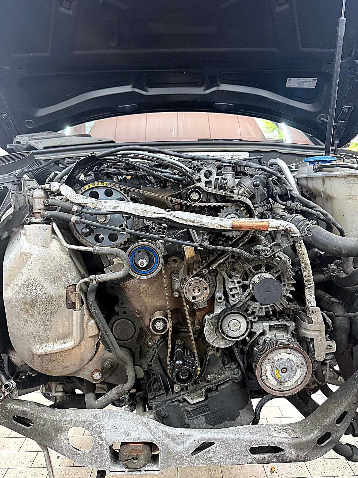 앞쪽 부품을 떼어 내 드러난 아우디 A4 TDI 엔진 앞면의 타이밍벨트와 겉벨트