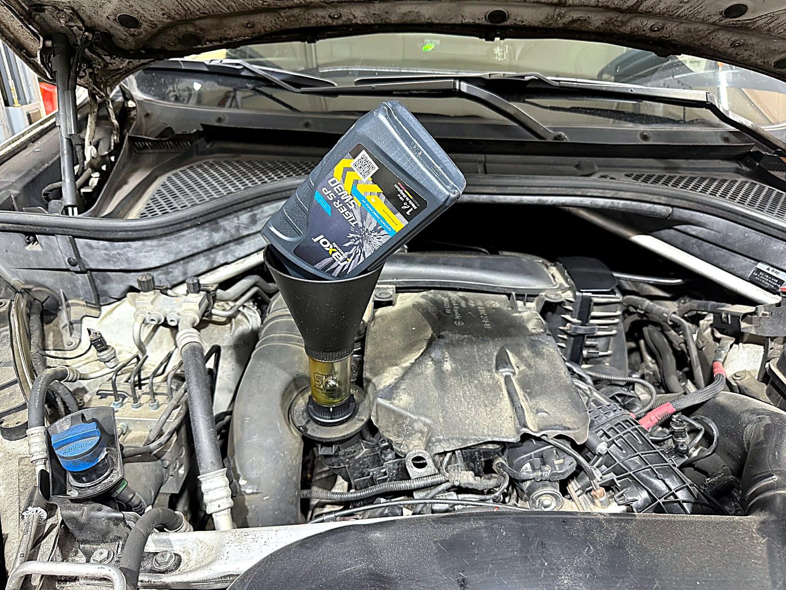BMW X5 엔진에 새 엔진오일을 주입하는 모습